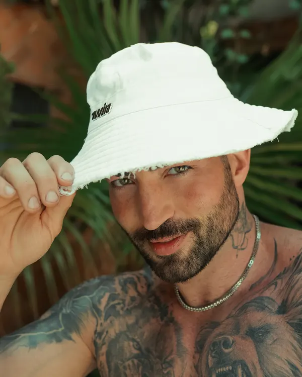 Maximo Garcia in a white bucket hat, smiling at the camera
