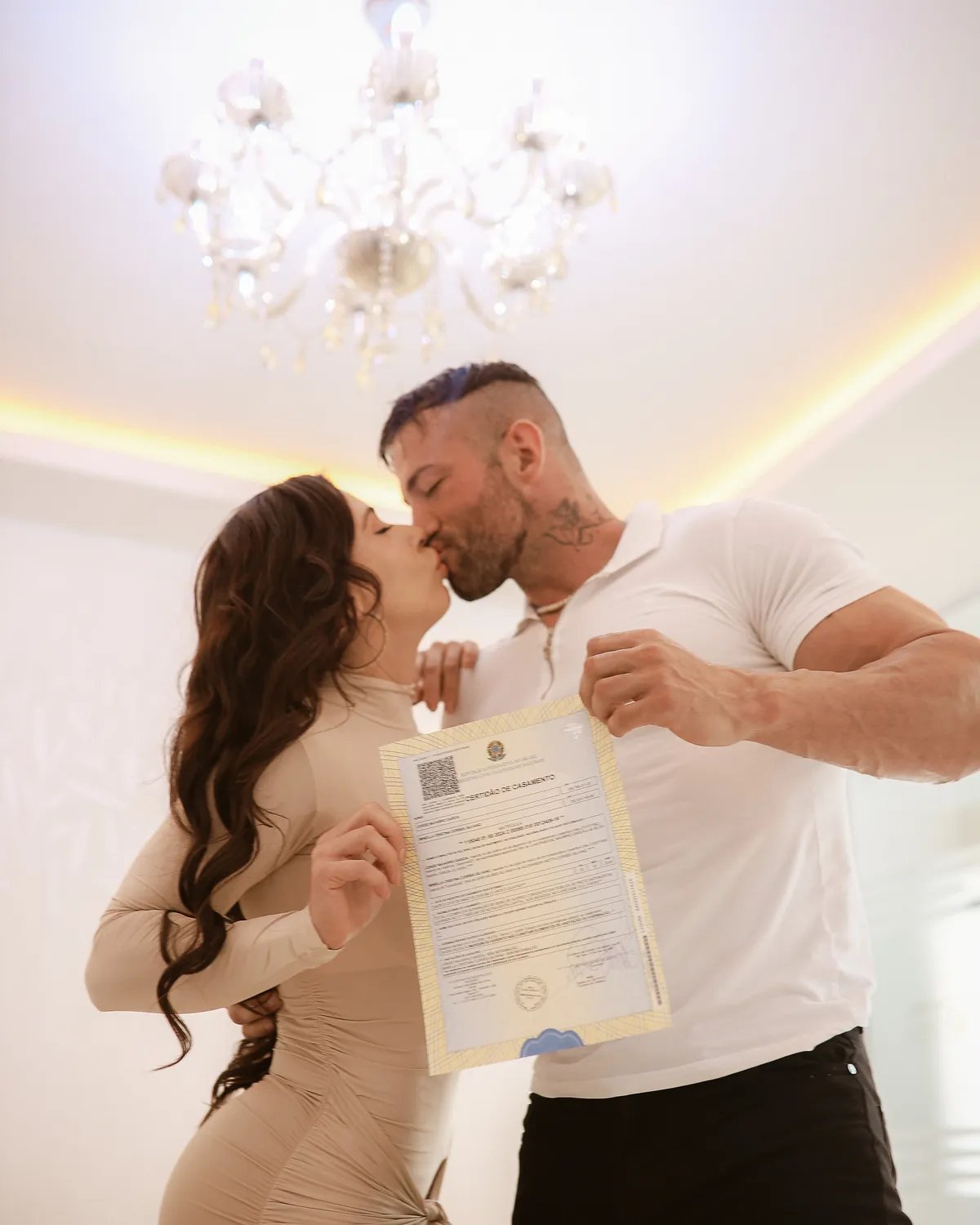 Maximo Garcia with a woman in a bright room, holding a signed document